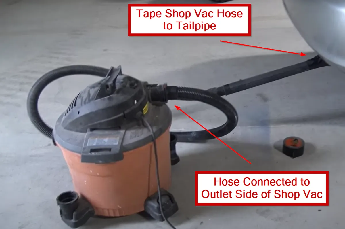 Shop-vacuum outlet hose connected at the Camry tailpipe